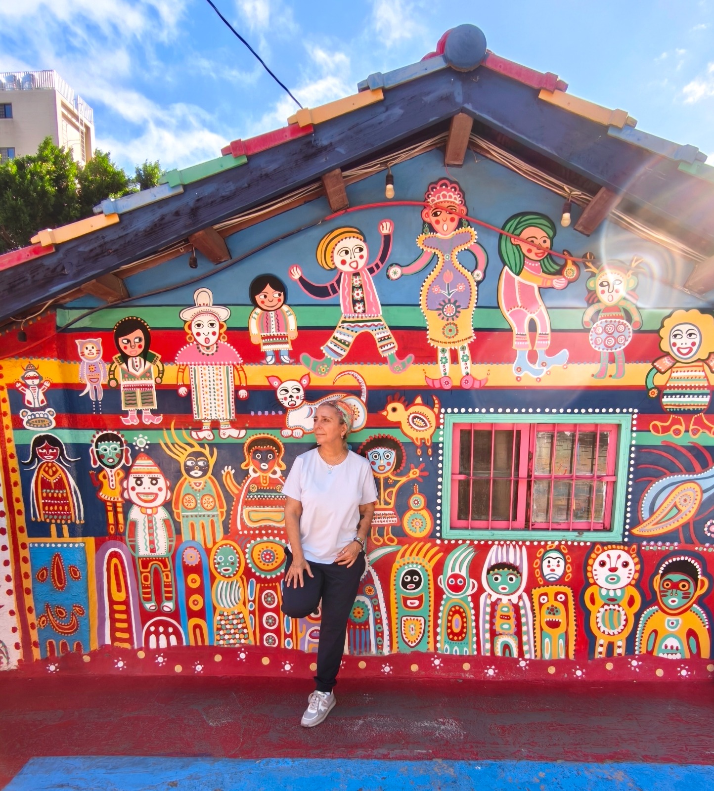 Rosa delante de una casa con un mural de colores