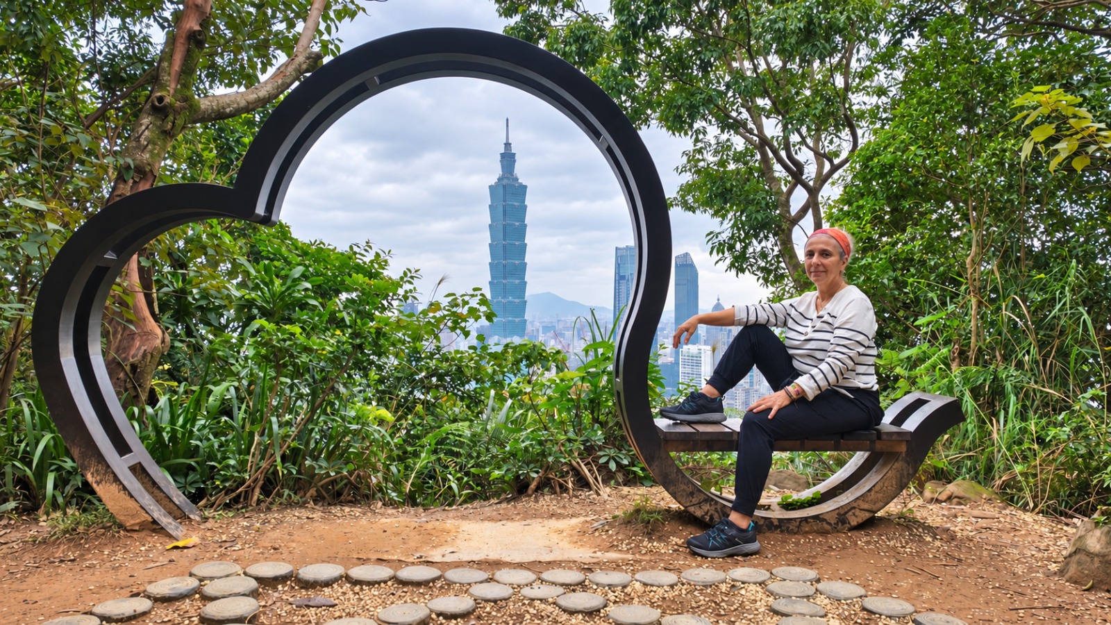 Rosa sentada junto a una escultura con Taipei 101 al fondo